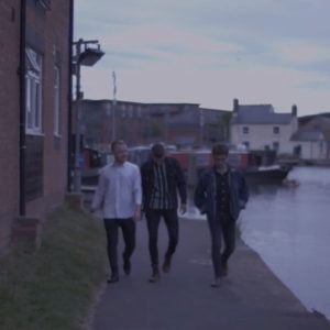 Three men walking along the side of a canal
